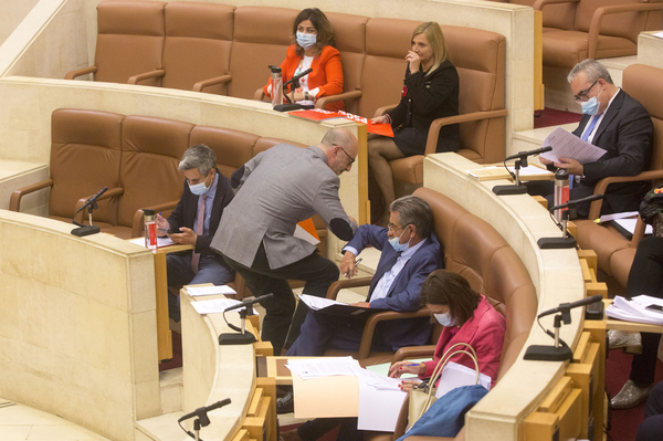 Félix Álvarez y Miguel Ángel Revilla se saludan con el codo en la sesión parlamentaria de este lunes. Foto: Celedonio