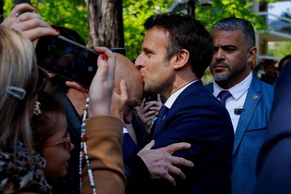 El presidente y candidato liberal Emmanuel Macron besa la calva de un simpatizante para tener buena suerte en esta jornada electoral. Fuente: AFP