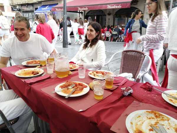 Los bares de la calle Tudela reparten hamaiketakos sin descanso. Las reservas se realizaron hace días y las cuadrillas cogen fuerzas para el txupinazo. Cinthya, camarera del café Manterola, reparte los típicos platos de txistorra con tomate, jamón y huevo frito.