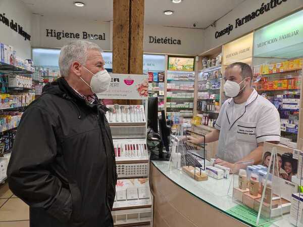 Mario Cortada, de la farmacia Mónica Martín Herrero, en la Avenida de Valdecilla atiende a José Antonio Vizueta, ambos con la mascarilla que sigue siendo obligatoria en estos establecimientos.